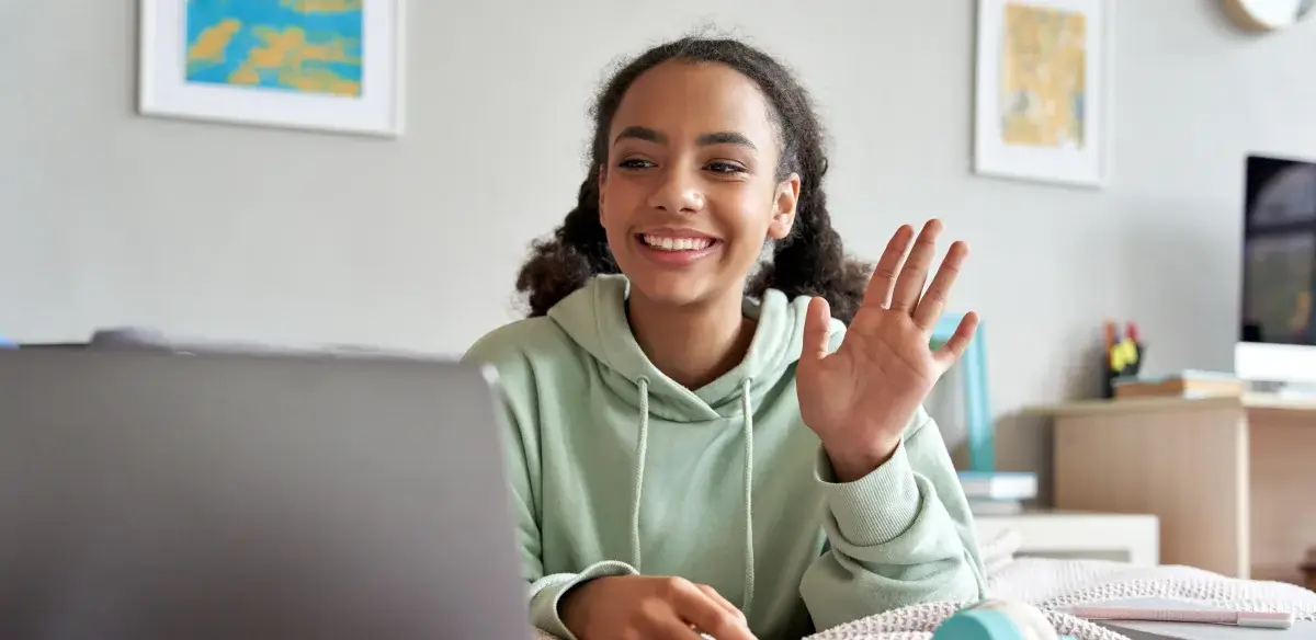 High school student wearing a light green hoodie attending to an online class
