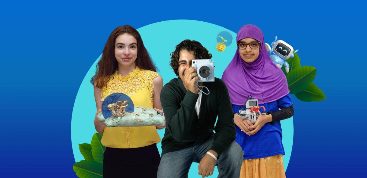Student holding an art project, another studing holding a camera and a girl holding a small robot